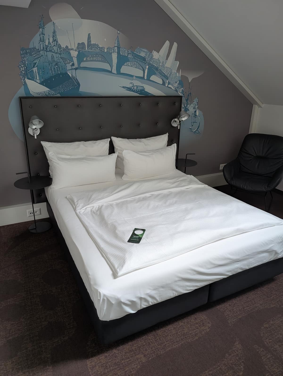 Ein Doppelzimmer im Motel One Basel mit dunklem Kopfteil und weisser Bettwäsche