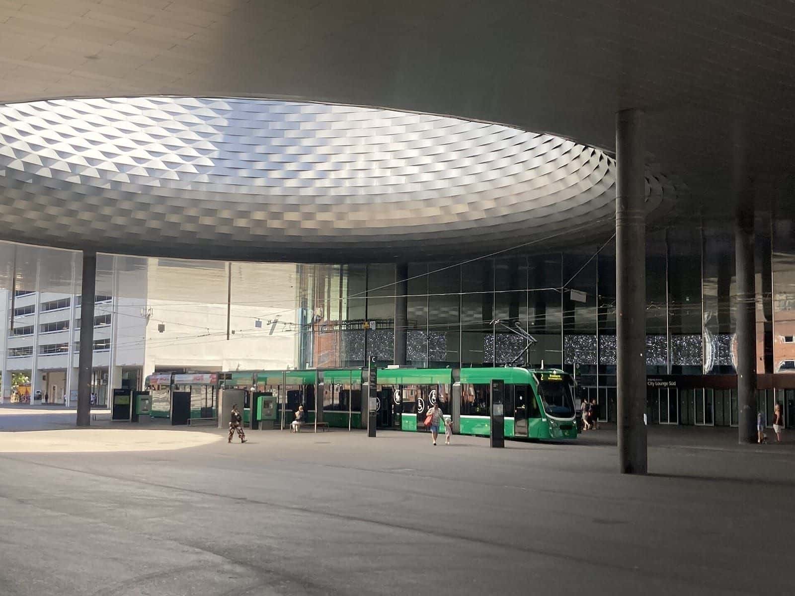 A green line 2 tram at the Messeplatz stop under the round opening in the roof of Hall 1