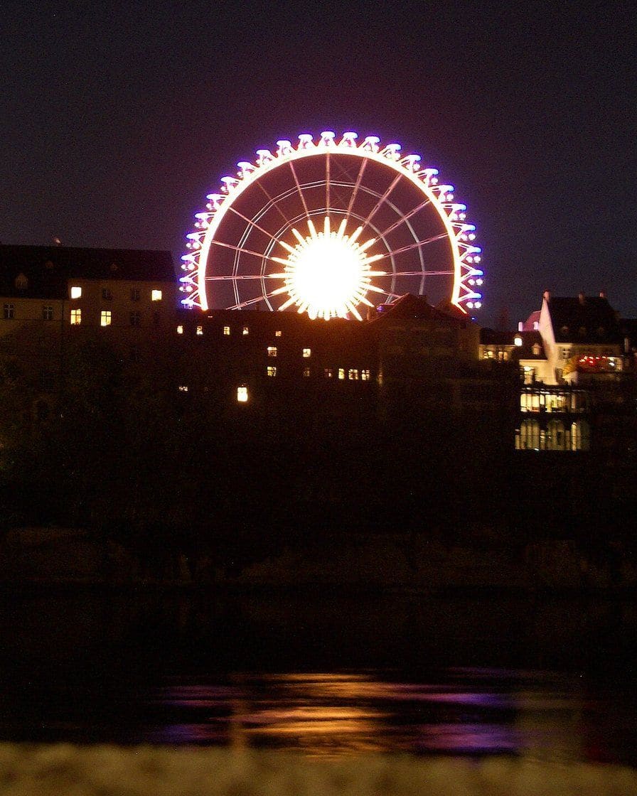 Das beleuchtete Riesenrad der Herbstmesse am Abend neben dem Basler Münster, über dem Rhein gesehen