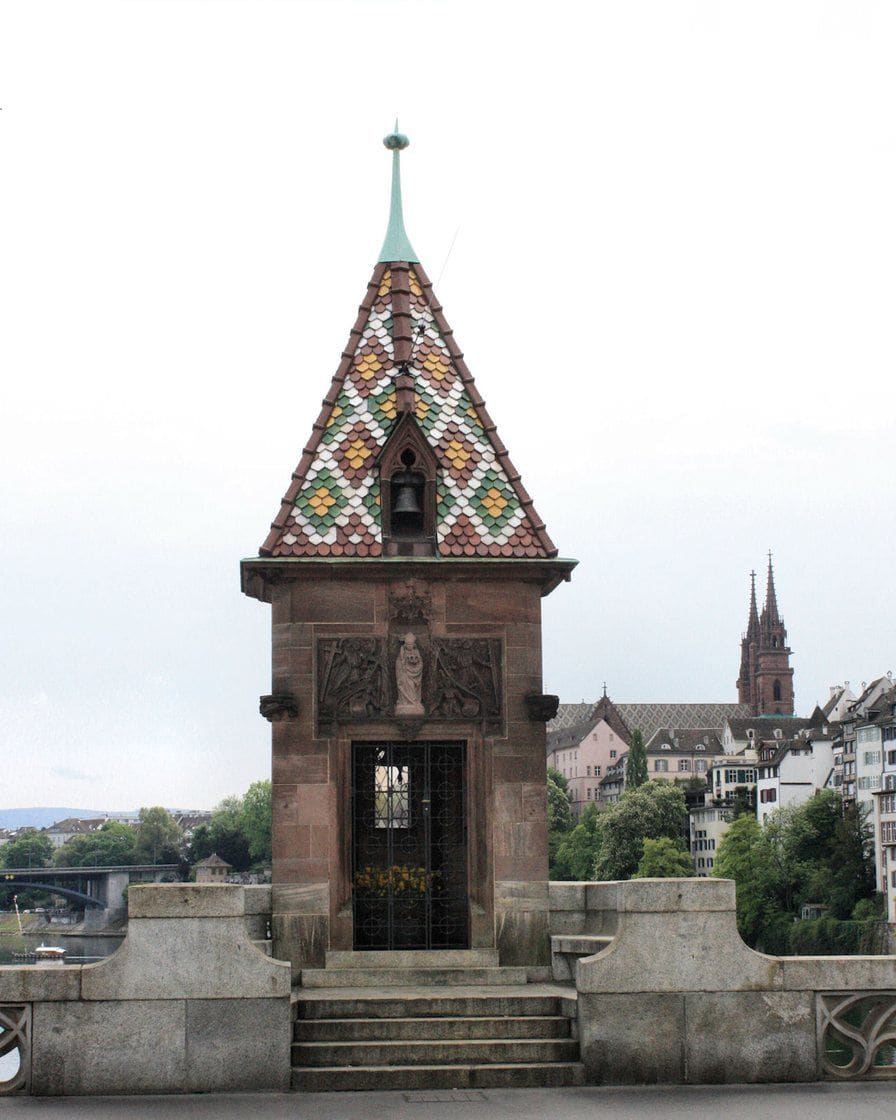 Das Käppelijoch auf der Mittleren Brücke mit seinem bunten Ziegeldach, dahinter das Münster über dem Rhein
