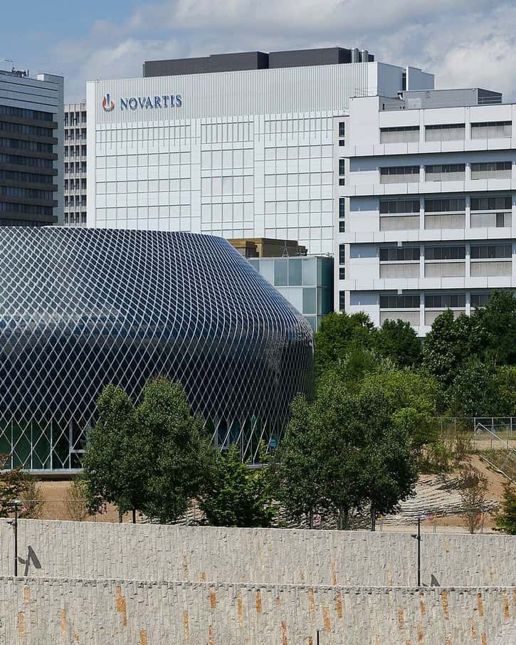 Der runde Novartis Pavillon in Basel mit seiner dunklen Hülle aus Solarmodulen zwischen den Campusbauten