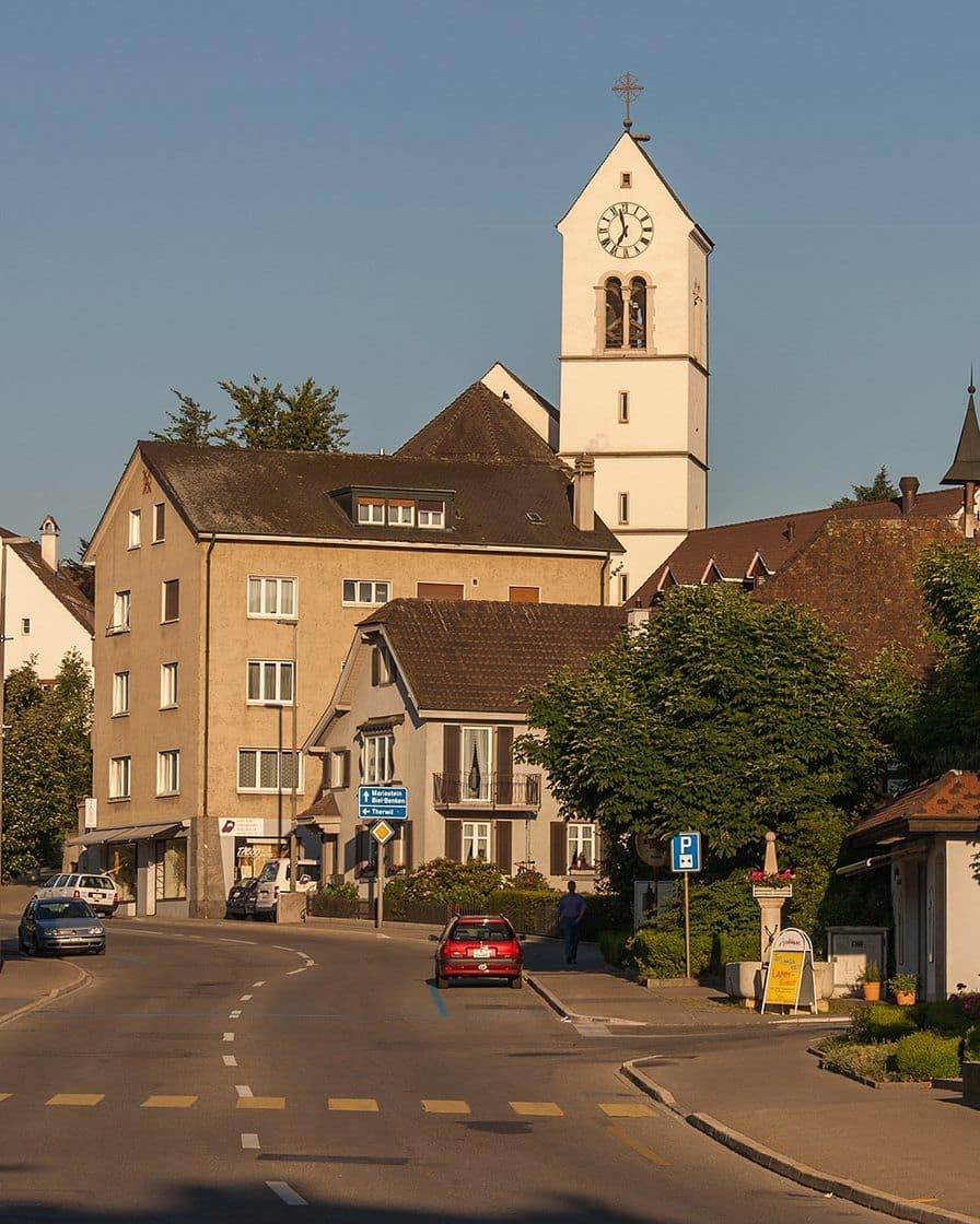 Das Zentrum von Oberwil im Leimental südlich von Basel, mit Kirchturm, Dorfstrasse und Bäumen, Endpunkt einer der Park-and-Ride-Routen