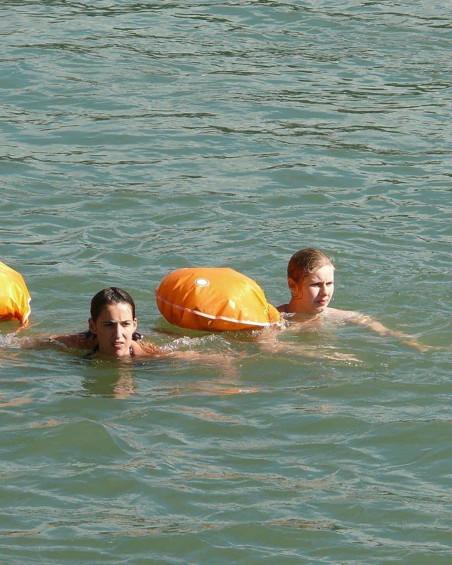 Zwei Schwimmer mit orangen Wickelfisch-Säcken lassen sich in Basel den Rhein hinuntertreiben