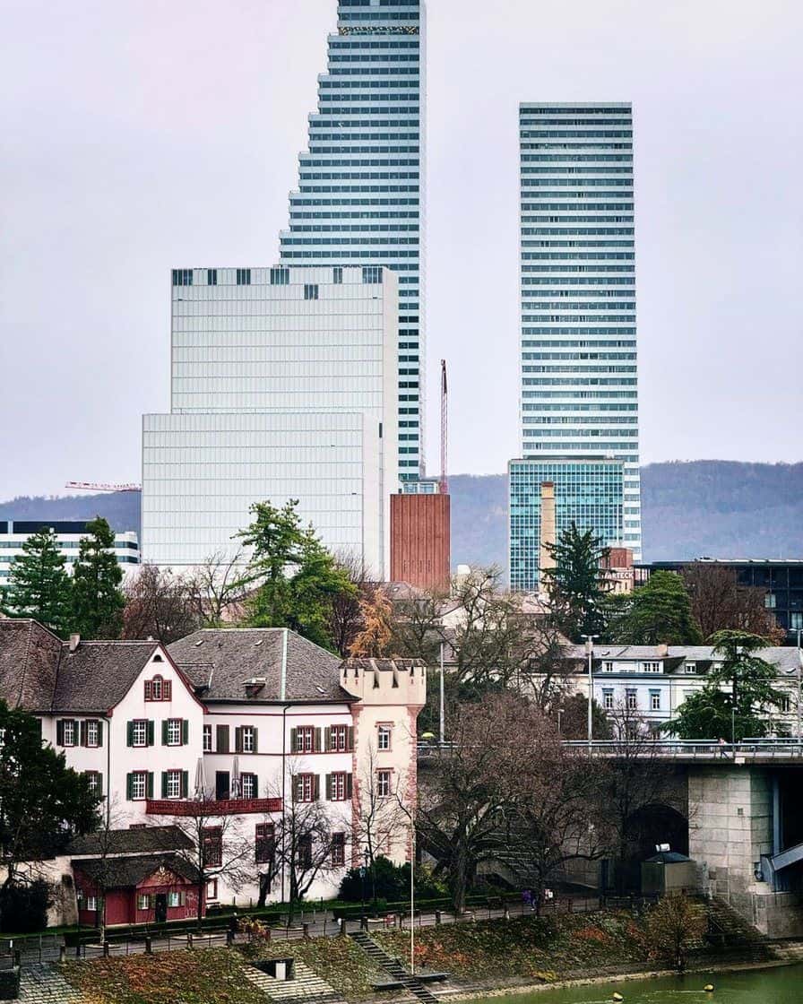Die beiden weissen Roche-Türme in Basel mit ihren gestuften Silhouetten, vom Rheinufer aus über die Dächer gesehen